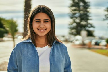 Genç Latin kız gülümseyerek şehirde mutlu mesut dikiliyor..