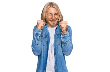 Sarışın, uzun saçlı, sıradan bir kot ceket giyen, kolları havada, gözleri kapalı zaferi kutlayan beyaz bir adam. Kazanan konsept. 