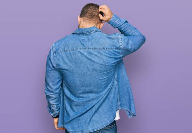 Kafkasyalı genç bir adam günlük kıyafetlerini ters giyip elleri kafasında şüpheyi düşünüyor. 