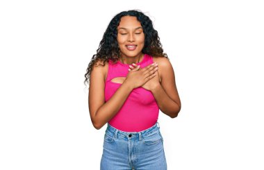 Kıvırcık saçlı, pembe bluzlu, elleri göğsünde, gözleri kapalı ve yüzünde minnet ifadesi olan İspanyol bir kadın. sağlık kavramı. 