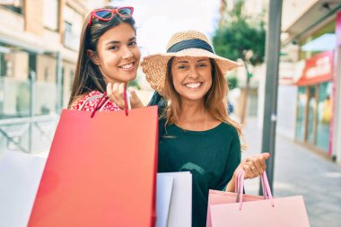 Güzel İspanyol anne ve kızı gülümseyerek şehirde mutlu ve alışveriş yapıyorlar..