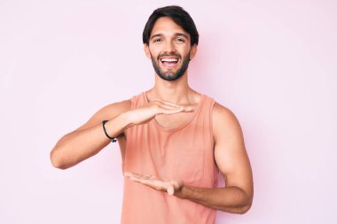 Yakışıklı, sıradan kıyafetler giyen, elleri büyük ve büyük boy işareti gösteren, ölçü sembolü olan bir İspanyol. Kameraya bakıp gülümsüyor. ölçüm kavramı. 