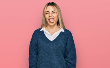 Gündelik giysiler giymiş genç beyaz kadın kameraya seksi bir ifadeyle bakıyor, neşeli ve mutlu bir yüzle.. 