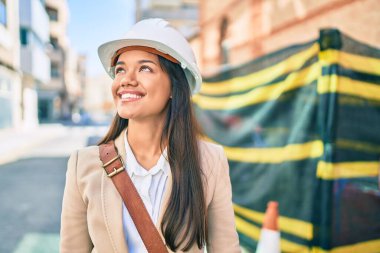 Genç, latin mimar kız gülümseyerek şehirde mutlu mesut duruyor..