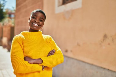Genç Afrikalı Amerikalı kadın gülümseyerek şehirde mutlu mesut duruyor..