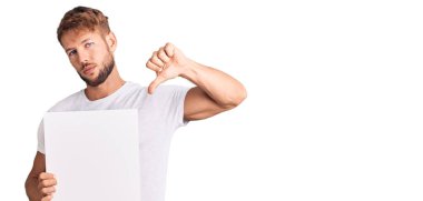 Kafkasyalı genç adam elinde boş pankart, kızgın surat, olumsuz işaret baş parmakları aşağıda, reddedilme konsepti. 