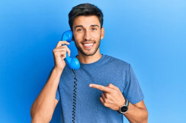 Bağbozumu telefonda konuşan yakışıklı genç adam mutlu bir şekilde el ve parmağıyla işaret ediyor. 