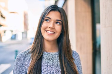 Genç ve güzel İspanyol kız gülümseyerek şehirde mutlu mesut yürüyor..