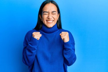 Sıradan bir kış kazağı giyen genç Asyalı kadın kolları havada ve gözleri kapalı zaferi kutlarken heyecanla bekliyor. Kazanan konsept. 