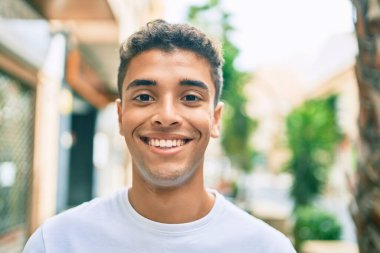 Genç Latin adam gülümseyerek şehirde mutlu mesut yürüyor..
