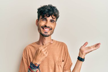 Gündelik kıyafetler giyen genç İspanyol adam kameraya hayret ediyor ve gülümsüyor.. 