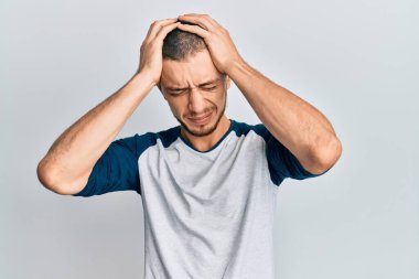 İspanyol genç adam gündelik kıyafetler giyip baş ağrısı çekiyor. Acı ve migren yüzünden çaresiz ve stresli. Eller başının üstünde.. 