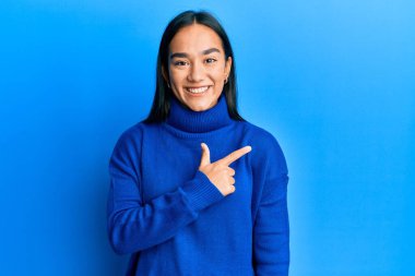 Genç Asyalı kadın, günlük kışlık süveter giyiyor. Neşeli, yüzünde gülümseme var. Yüzünde mutlu ve doğal bir ifade var. 