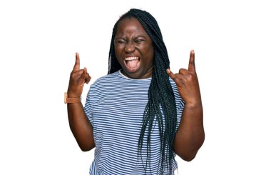 Saçları örgülü, sıradan kıyafetler giyen, çılgın bir ifadeyle bağıran, elleri havada rock sembolü yapan genç siyahi bir kadın. Müzik yıldızı. ağır kavram. 