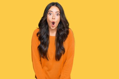 Güzel esmer, turuncu bir süveter giyen genç bir kadın. Korkmuş ve şaşırmış bir şekilde ağzı açık kalmış, inançsız bir yüz. 
