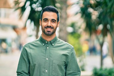 Genç İspanyol adam gülümseyerek şehirde mutlu mesut dikiliyor..