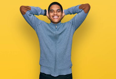 Genç, yakışıklı İspanyol adam rahat ve esnek, kolları ve elleri başının arkasında mutlu bir şekilde gülümsüyor. 