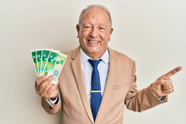 Starší Kavkazský Muž Držící Izraelské Šekely Šťastně Usmívá Ukazuje Rukou — Stock fotografie