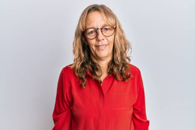 Yüzünde mutlu ve havalı bir gülümsemeyle orta yaşlı, sarışın bir kadın günlük kıyafetler ve gözlük takıyor. şanslı kişi. 