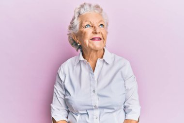 Kıdemli, gri saçlı, günlük kıyafetler giyen, rahat bir görünüm takınan, doğal yüzlü ve kendine güvenen bir gülümseme takınan bir kadın.. 