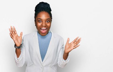 Genç Afro-Amerikan kadın iş kıyafetleri giyip çılgınlığı kutluyor ve başarıya hayret ediyor kolları açık ve gözleri açık heyecanla bağırıyor. Kazanan konsept 