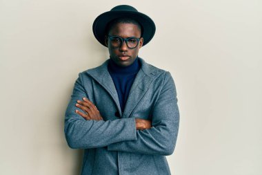 Genç Afro-Amerikan erkeği zarif bir stil giyiyor şüpheci ve gergin, yüzünde çapraz kollu tasvip etmeyen bir ifade. negatif kişi. 