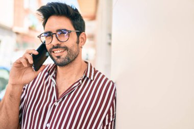 Sakallı, yakışıklı, dışarıda mutlu bir şekilde gülümseyen telefonda konuşan genç bir İspanyol.