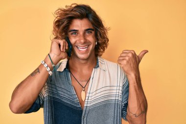 Genç İspanyol adam akıllı telefondan konuşuyor. Parmağını kaldırıyor, gülümsüyor, ağzı açık. 