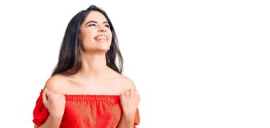 Esmer, sıradan kıyafetler giyen, başarı için heyecanlanan kolları havada, gözleri kapalı zaferi kutlayan genç kız. Kazanan konsept. 