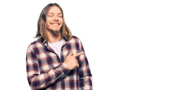 Uzun saçlı, yakışıklı, beyaz, hippi tişörtlü, yüzünde mutlu ve doğal bir ifadeyle, elleri ve parmaklarıyla yüzünü gösteren bir gülümseme. 