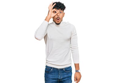 Sıradan bir kazak giyen genç bir Arap, şaşırmış yüz ifadesiyle şaşırmış, parmaklarından bakan bir jest yapıyor. İnançsız ifade. 