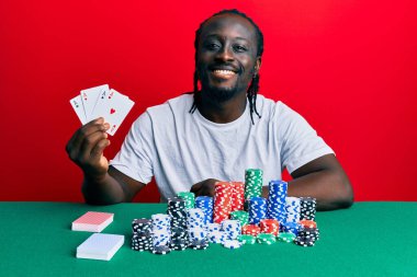 Poker oynayan yakışıklı genç bir adam. Pozitif ve mutlu görünüyor. Kendine güvenen bir gülümsemeyle dişlerini gösteriyor. 