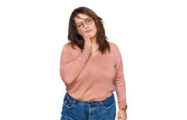 Genç ve cüsseli bir kadın günlük kıyafetler giyiyor ve kollarını kavuşturarak depresyondan sıkılmış ve yorgun görünüyor.. 