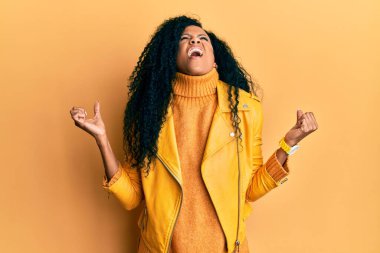 Middle age african american woman wearing wool winter sweater and leather jacket crazy and mad shouting and yelling with aggressive expression and arms raised. frustration concept. 