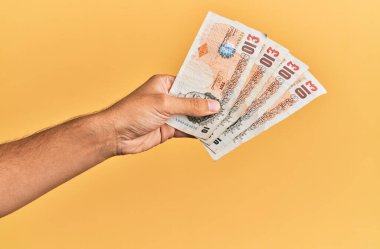 İspanyol bir adamın elinde 5 kilo banknotla izole edilmiş sarı arka plan..