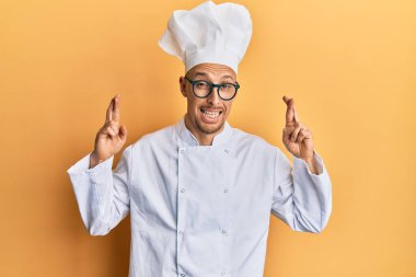 Profesyonel aşçı üniforması giyen kel bir adam umut ve gözlerin kapalı gülümseyerek işaret ediyor. Şans ve batıl inançlar. 