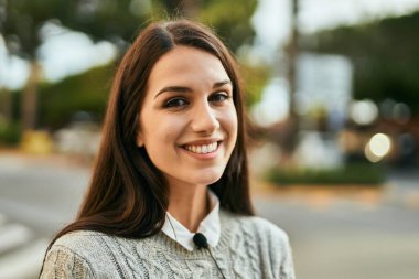 Genç İspanyol kadın gülümseyerek şehirde mutlu mesut dikiliyor..