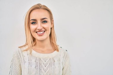 Genç sarışın kız gülümsüyor, mutlu bir şekilde şehirde duruyor..