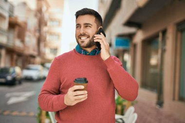 Genç İspanyol adam akıllı telefondan konuşuyor. Şehirde kahve içiyor..