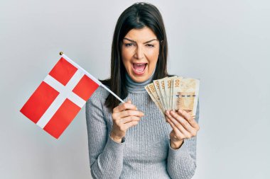 Genç İspanyol kadın elinde Danimarka bayrağı ve Krone banknotları tutarken kahkahalarla gülüyor.. 