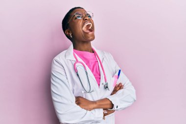 Young african american woman wearing doctor uniform and stethoscope angry and mad screaming frustrated and furious, shouting with anger looking up. 