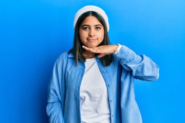 Şirin yün şapka takan, boğazını bıçak niyetine kesen, saldırganlığı şiddetle tehdit eden genç Latin bir kadın. 