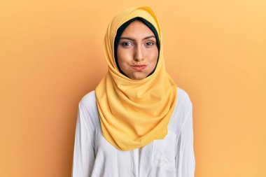 Geleneksel İslami başörtüsü takan esmer Arap kadın komik yüzlü yanakları şişiriyor. Havayla şişmiş ağız, çılgın bir ifade.. 