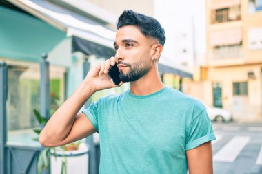 Şehirdeki akıllı telefondan konuşan, ciddi bir suratı olan genç bir Arap..