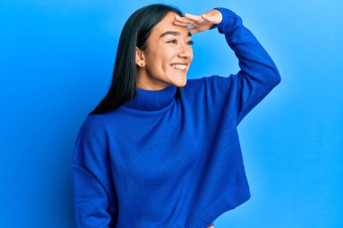 Genç Asyalı kadın, günlük kışlık süveter giyiyor. Çok mutlu ve gülümsüyor. Başını kaldırıp uzaklara bakıyor. arama kavramı. 