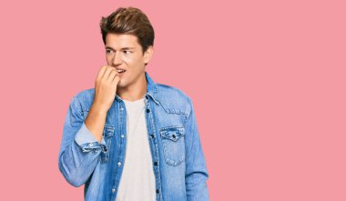 Sıradan kot ceket giyen yakışıklı, gergin ve ağzı tırnak yiyen elleri olan beyaz bir adam. anksiyete. 