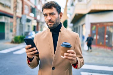 Zarif ceketli yakışıklı bir iş adamı. Açık havada akıllı telefon kullanıyor.