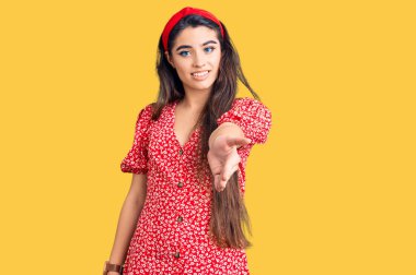 Yazlık elbise giyen esmer bir genç kız neşeli bir şekilde gülümseyerek avuç içi yardım ve kabullenme teklif ediyor.. 