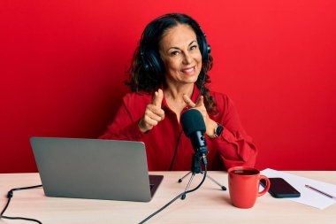 Radyo stüdyosunda çalışan orta yaşlı güzel bir kadın mutlu ve komik yüzüyle kamerayı işaret ediyor. iyi enerji ve titreşimler. 