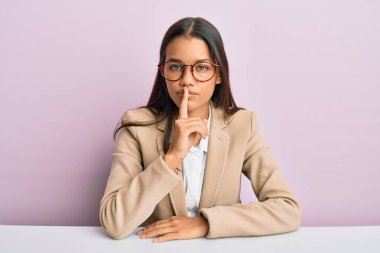 Ofiste çalışan güzel İspanyol kadın parmakları dudaklarında sessiz olmak istiyor. sessizlik ve gizli konsept. 